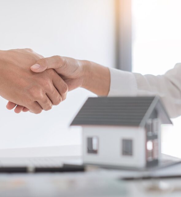 Estate agent in suit sitting in an office desk shaking hands with customer after contract signature accept agreement finish buying or rental real estate for transfer right of property
