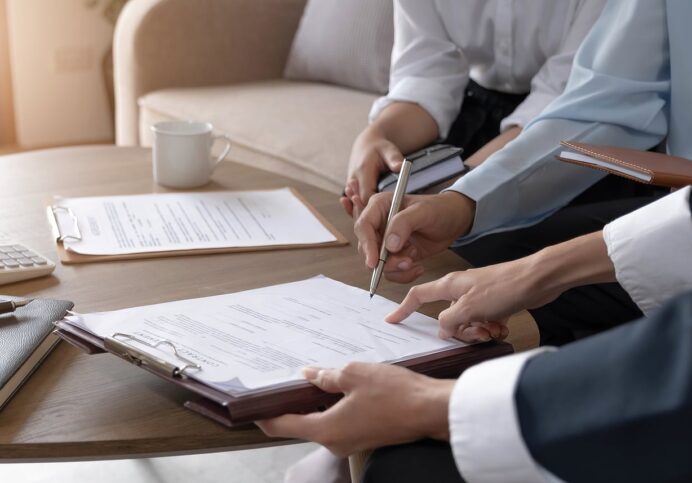 Real Estate Agent Explaining And Let Customers Sign A House Purchase
